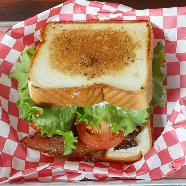 A Busta's Burgers BLT sandwich with crispy bacon, lettuce, and tomato on toasted bread.