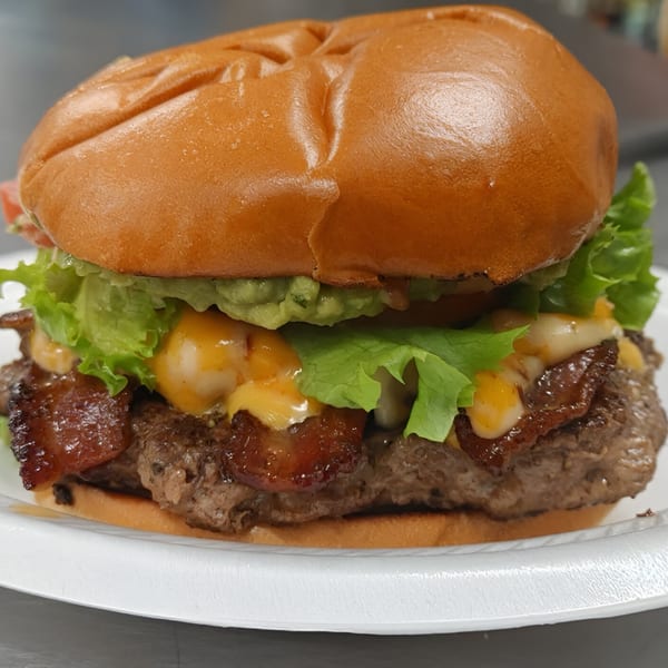 A Busta's Burger with bacon, cheese, lettuce, and guacamole on a white plate.